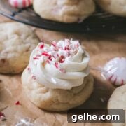 close up view of a peppermint sugar cookie topped with vanilla frosting and crushed peppermint candies.