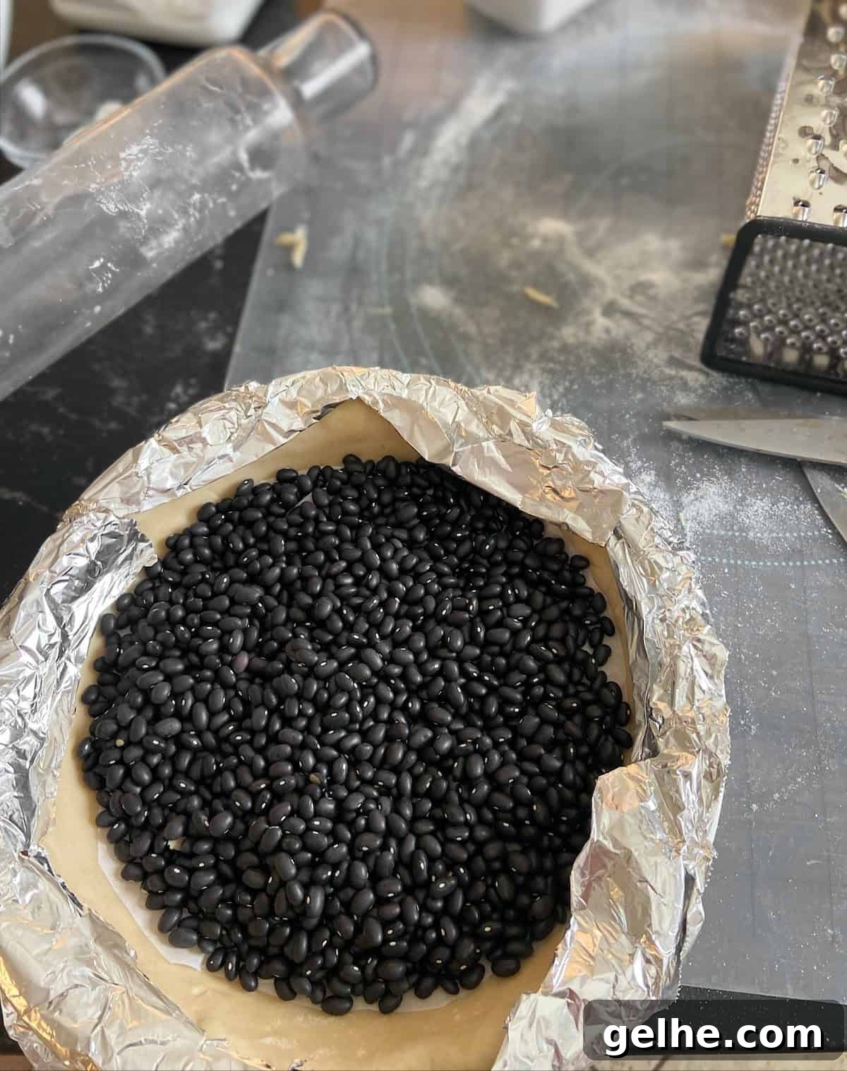 Classic Southern Pecan Pie Recipe: Authentic, Easy-to-Follow Instructions 5 Dried black beans on raw pie crust lined with foil.
