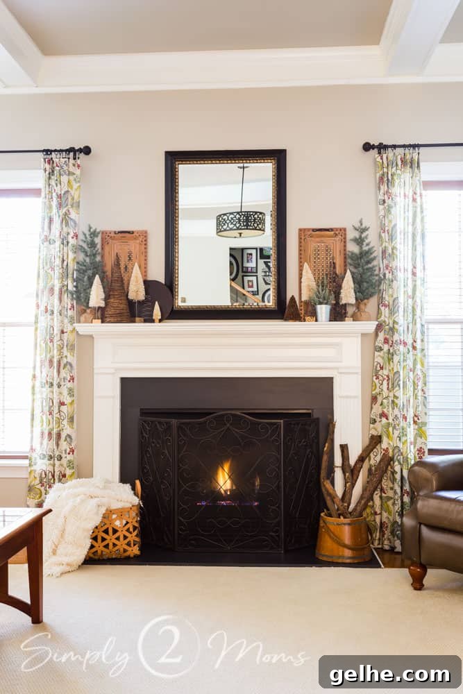 Cozy Neutral Vintage Farmhouse Winter Mantel Ideas 3 view of family room with fireplace lit and mantel decorated for winter with a variety of small trees.