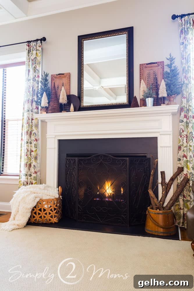 Cozy Neutral Vintage Farmhouse Winter Mantel Ideas 7 view of family room with fireplace lit and mantel decorated for winter with a variety of small trees.