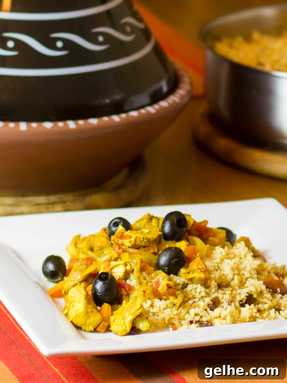 Mediterranean Chicken Tagine with Black Olives and Preserved Lemon 2 Tagine and couscous on a white square plate.