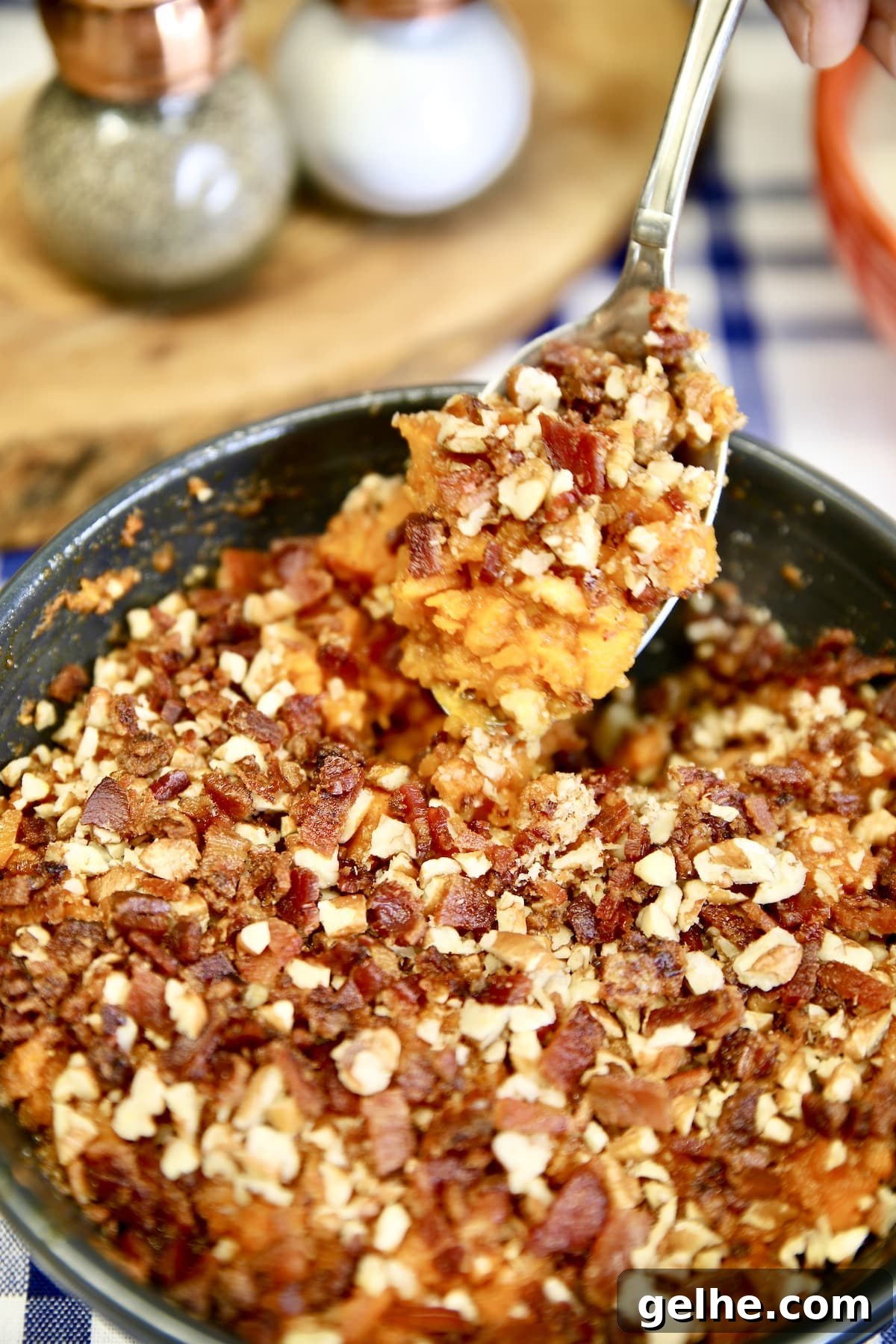 Grilled Sweet Potato Casserole is a delicious side dish to add to any holiday menu. Sweet potatoes are easy to grill right alongside your main dish and then mashed with butter and brown sugar, topped with bacon and pecans. Spoonful of sweet potatoes topped with bacon and pecans.