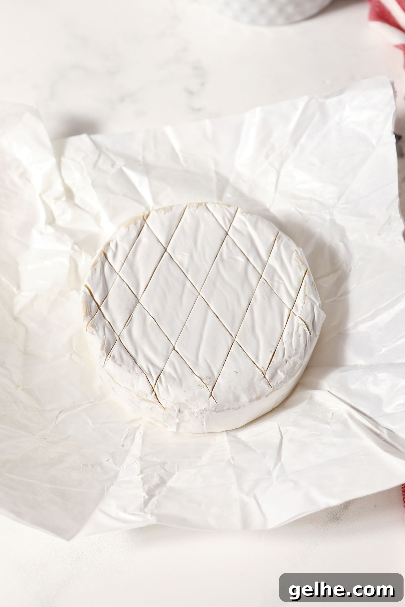 Closeup of a scored wheel of brie on paper