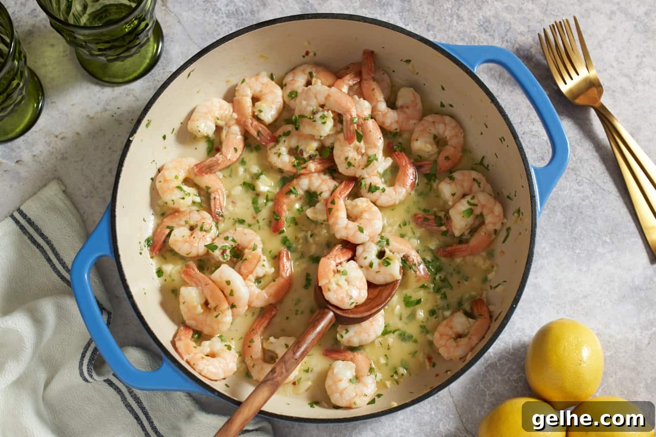 Quick Shrimp Scampi with Lemony Garlic Sauce 2 Shrimp scampi in a pan with blue handles with a wooden spoon in it. The pan is surrounded by two green glasses, three gold forks, three lemons, and a blue and white striped napkin.