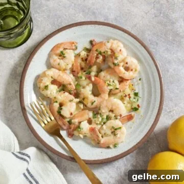 Quick Shrimp Scampi with Lemony Garlic Sauce 10 Shrimp scampi on a plate with a gold fork. The plate is surrounded by a green glass, three lemons, and a blue and white striped napkin.