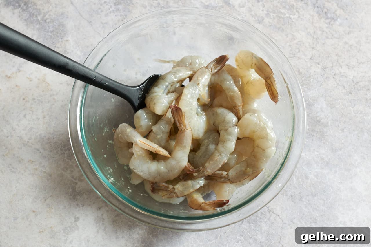 Quick Shrimp Scampi with Lemony Garlic Sauce 5 A glass bowl of shrimp with a black spatula in it.