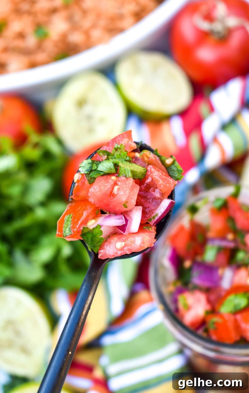 a black spoon holding up a scoop of homemade pico de gallo