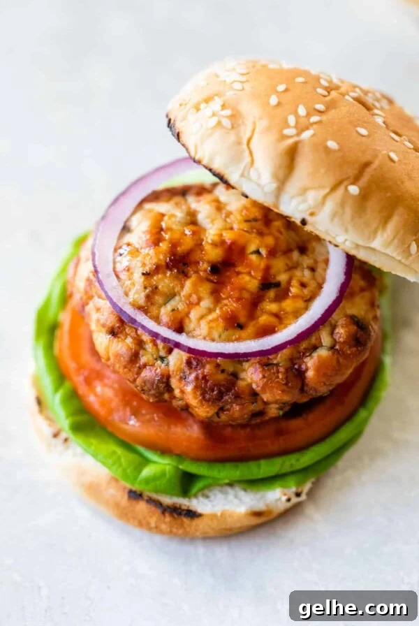 a turkey burger sandwich with a bun, lettuce, tomato, and red onion