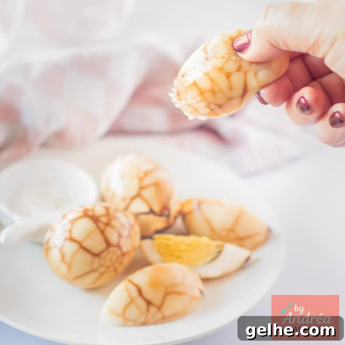 How to Make Chinese Tea Eggs: Savory Marble Egg Recipe 9 A square picture with tea eggs on a plate, some quartered, and a hand picking one of them.
