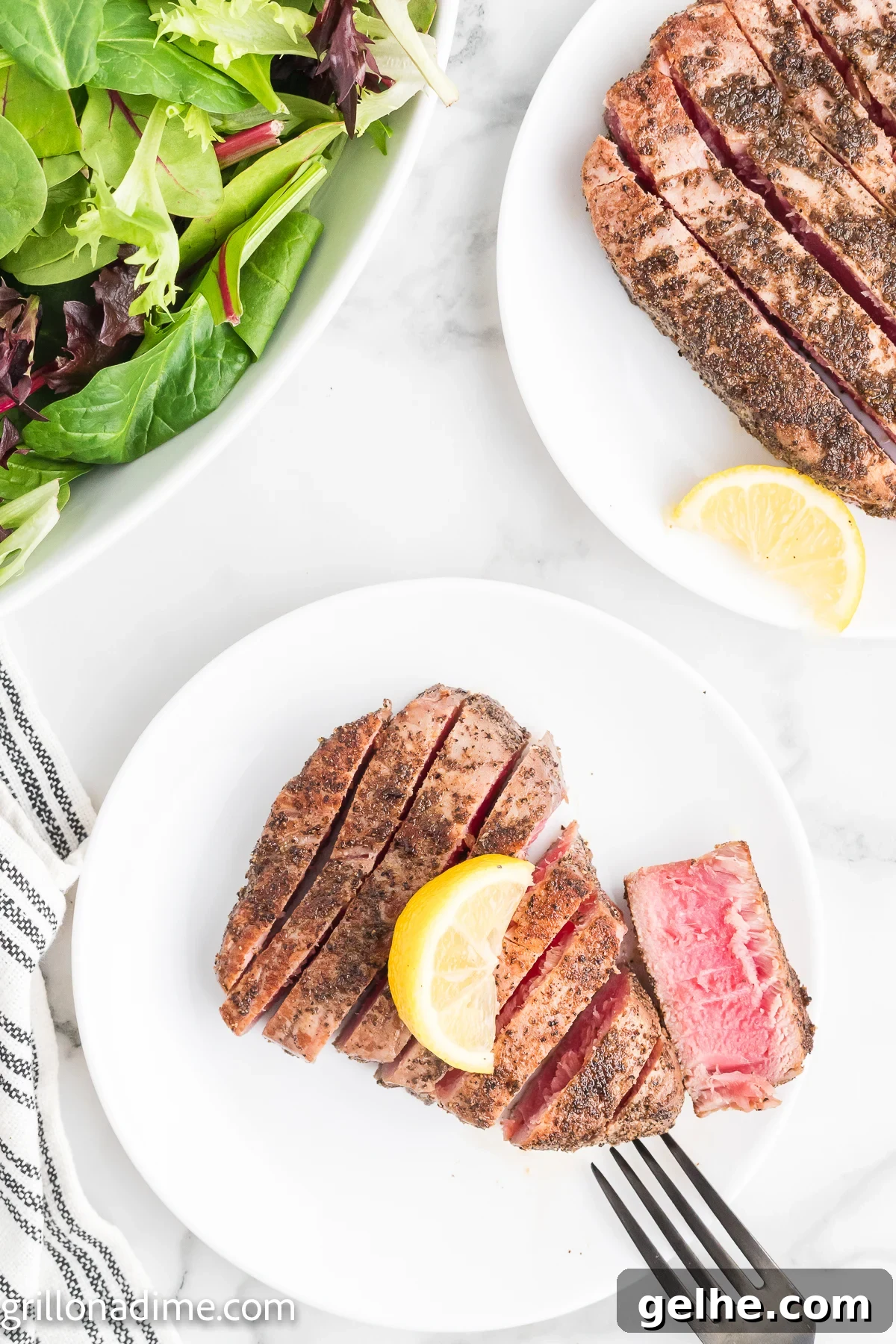 Tuna Steaks sliced on a plate topped with lemon wedges
