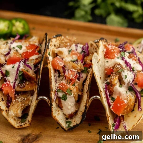 Freshly made grilled fish tacos with vegetables on a wooden serving board.