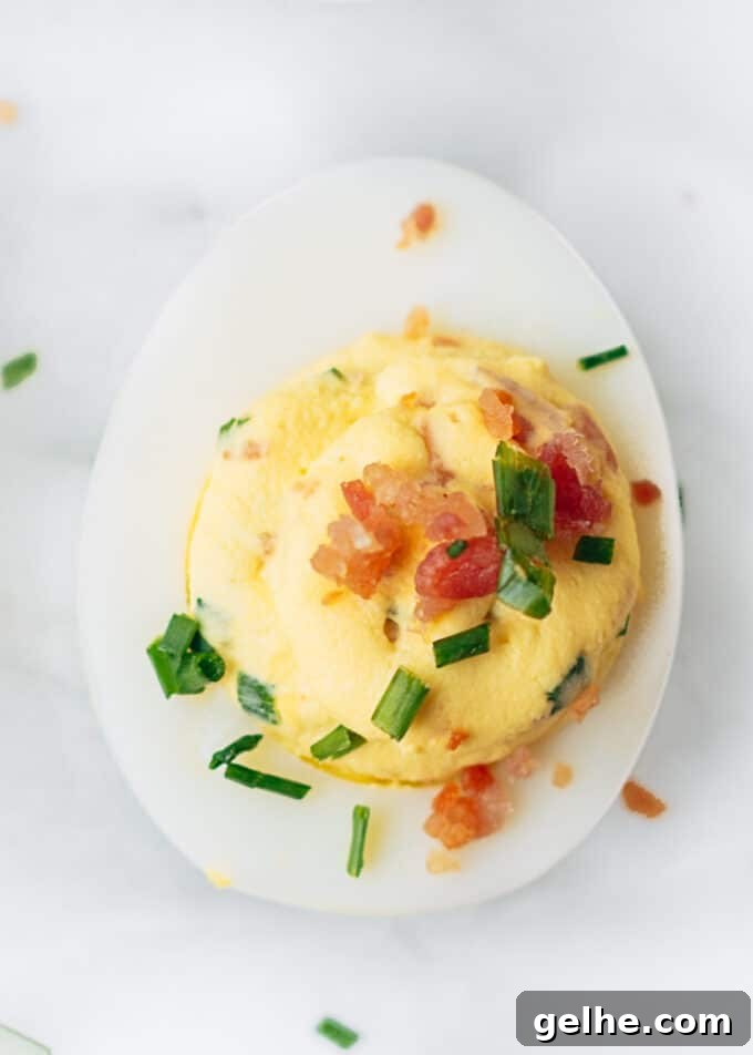 Bacon-Stuffed Deviled Eggs with Zesty Horseradish 2 bacon deviled egg with horseradish and chives on a marble board