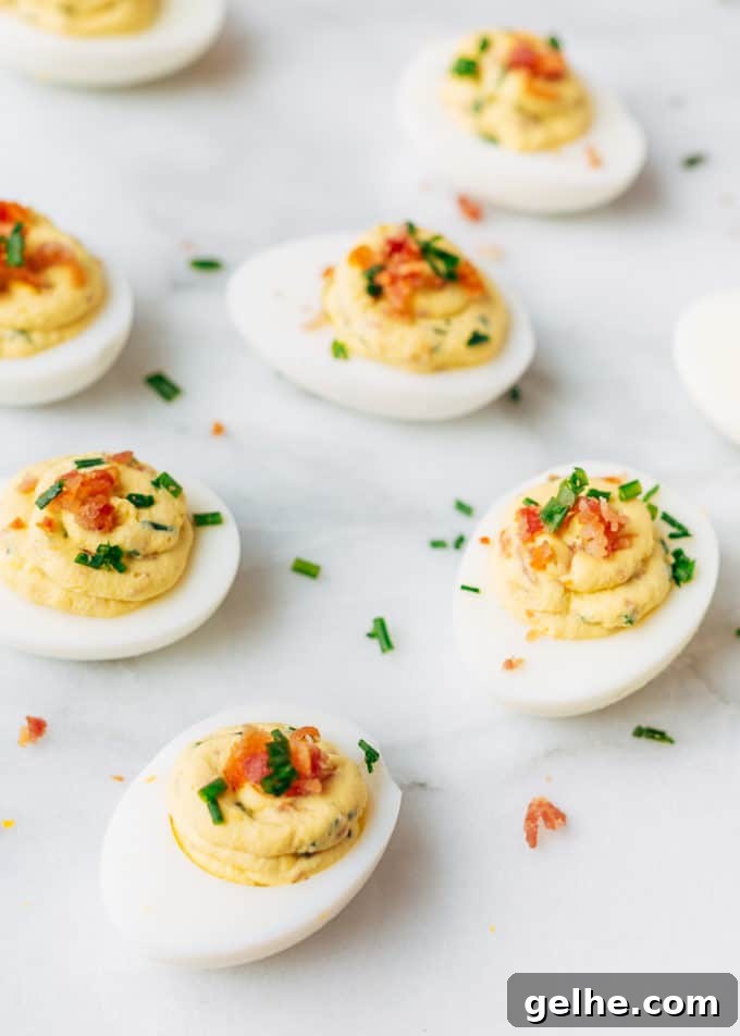Bacon-Stuffed Deviled Eggs with Zesty Horseradish 5 filled deviled eggs with bacon and horseradish on a white marble board