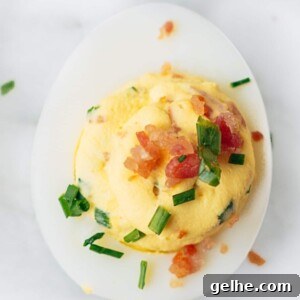 bacon deviled egg with horseradish and chives on a marble board