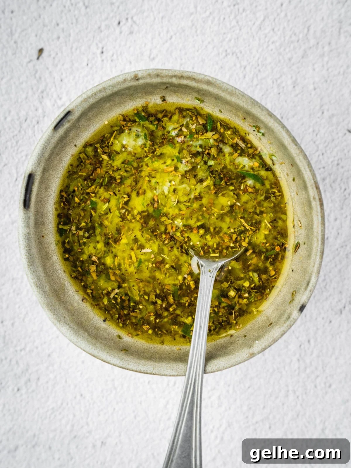 A bowl with olive oil, garlic, and herbs.