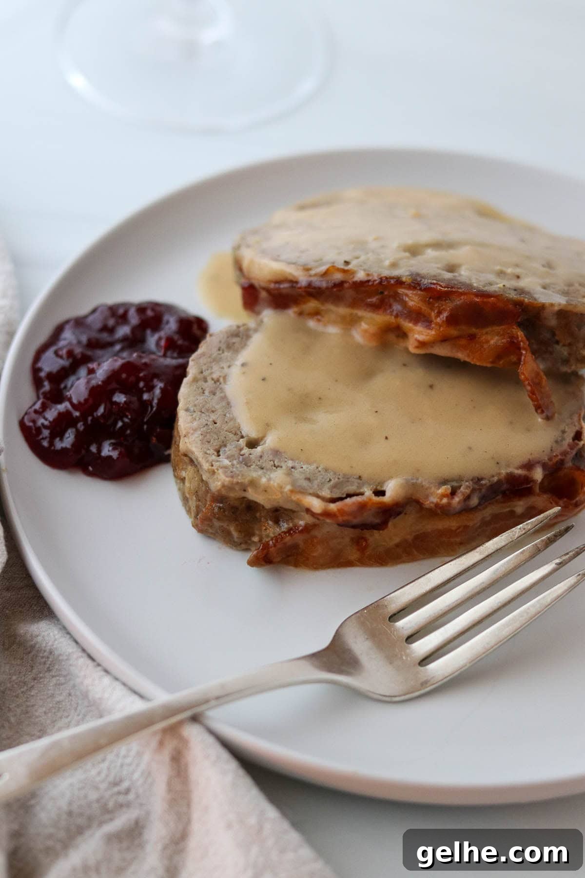 Danish Meatloaf on a plate with lingonberries and a fork.