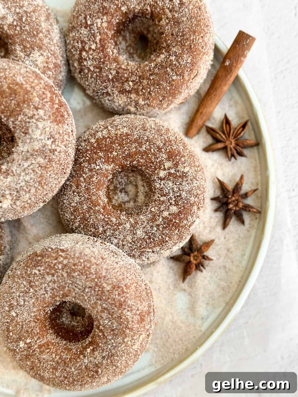 Baked Apple Cider Donuts Recipe | Light Autumn Donut Treat 11 a bunch of baked apple cider donuts on a plate covered in cinnamon and sugar.