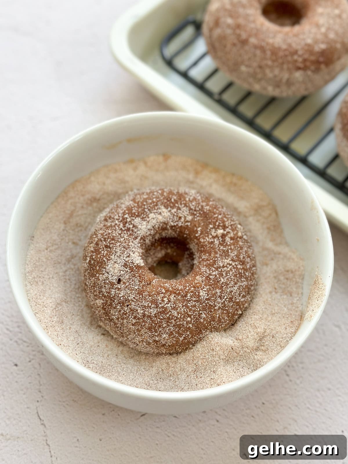 Baked Apple Cider Donuts Recipe | Light Autumn Donut Treat 9 apple cider donuts in cinnamon sugar bowl.
