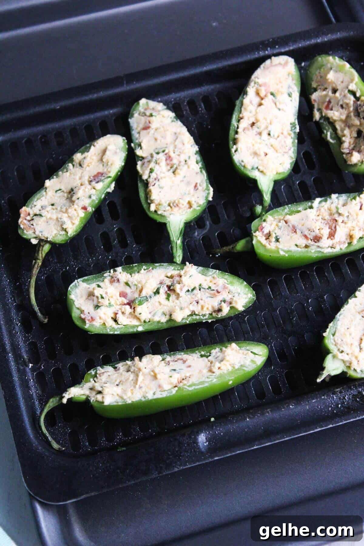 Peppers stuffed with filling on air fryer tray.