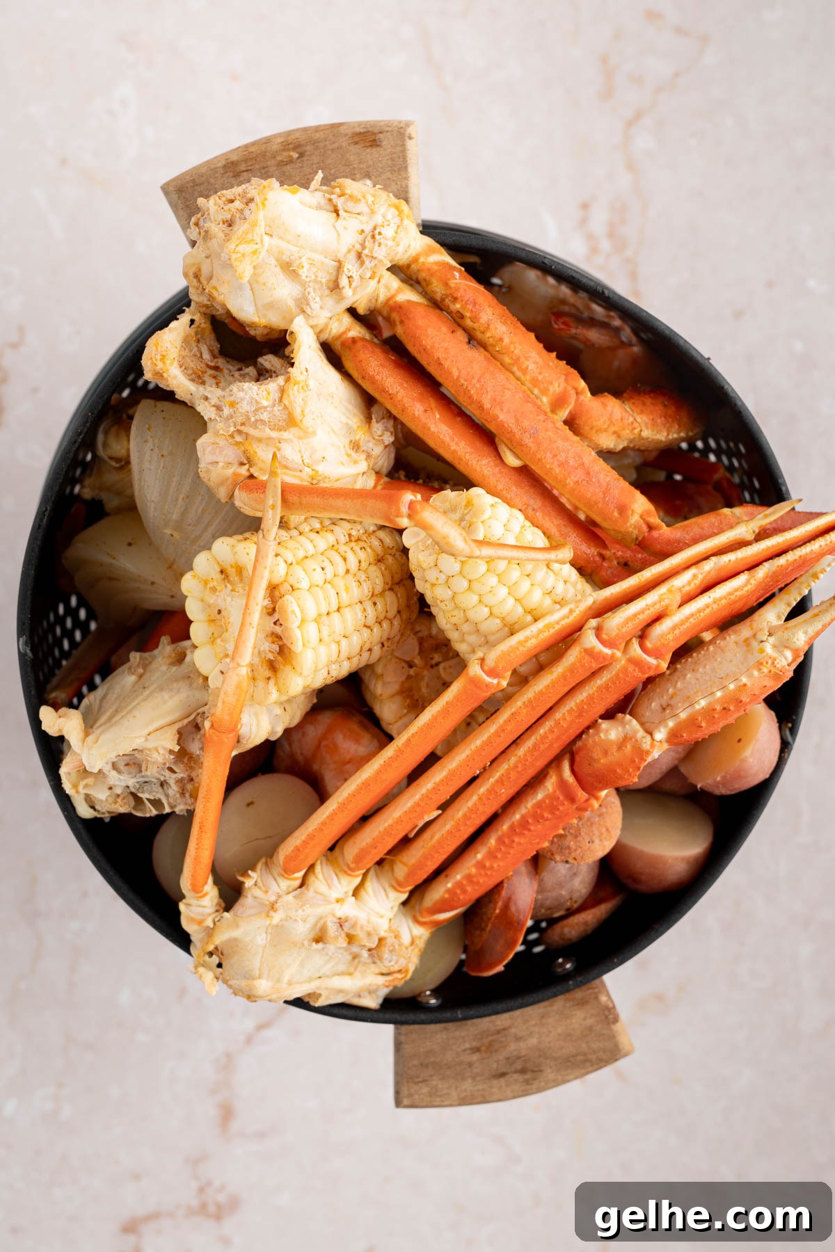 The drained corn, potatoes, shrimp, and crab claws in a colander.