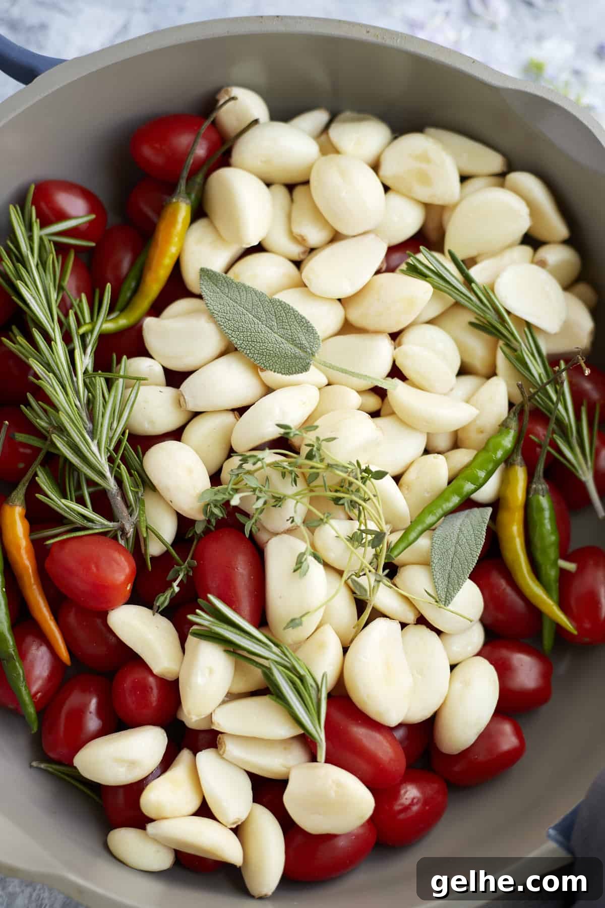 closeup overhead pan with tomatoes, chili peppers, garlic, and herbs