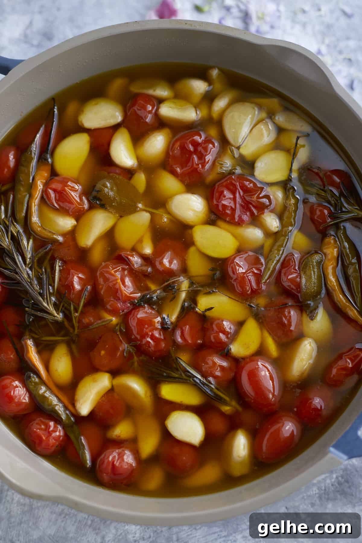 overhead pan with tomatoes, chili peppers, garlic, herbs, in olive oil