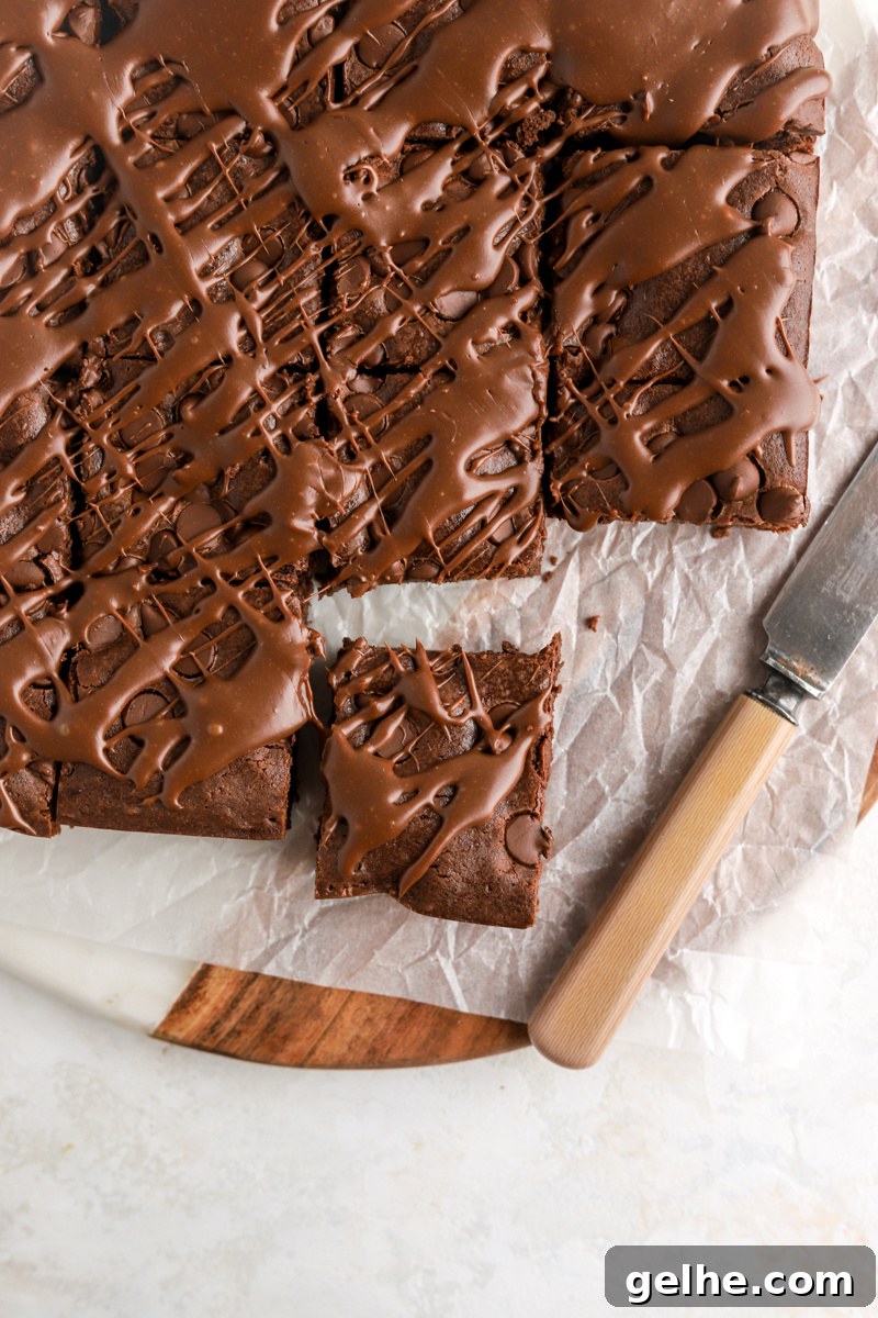Fudgy Condensed Milk Brownies with a Creamy Caramel Swirl 9 Brownies with chocolate chips and chocolate sauce on top cut into squares.