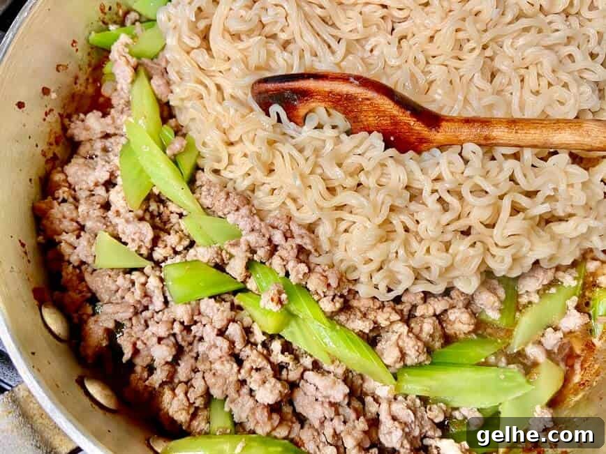 Adding cooked noodles to the pan.