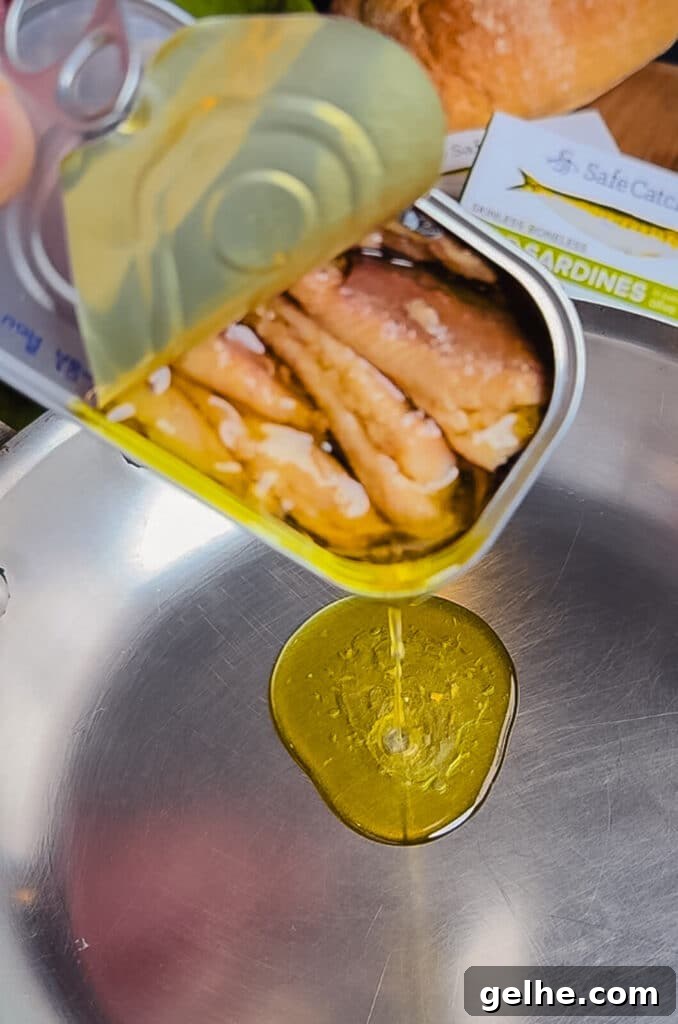 oil pouring from a sardine can into a skillet