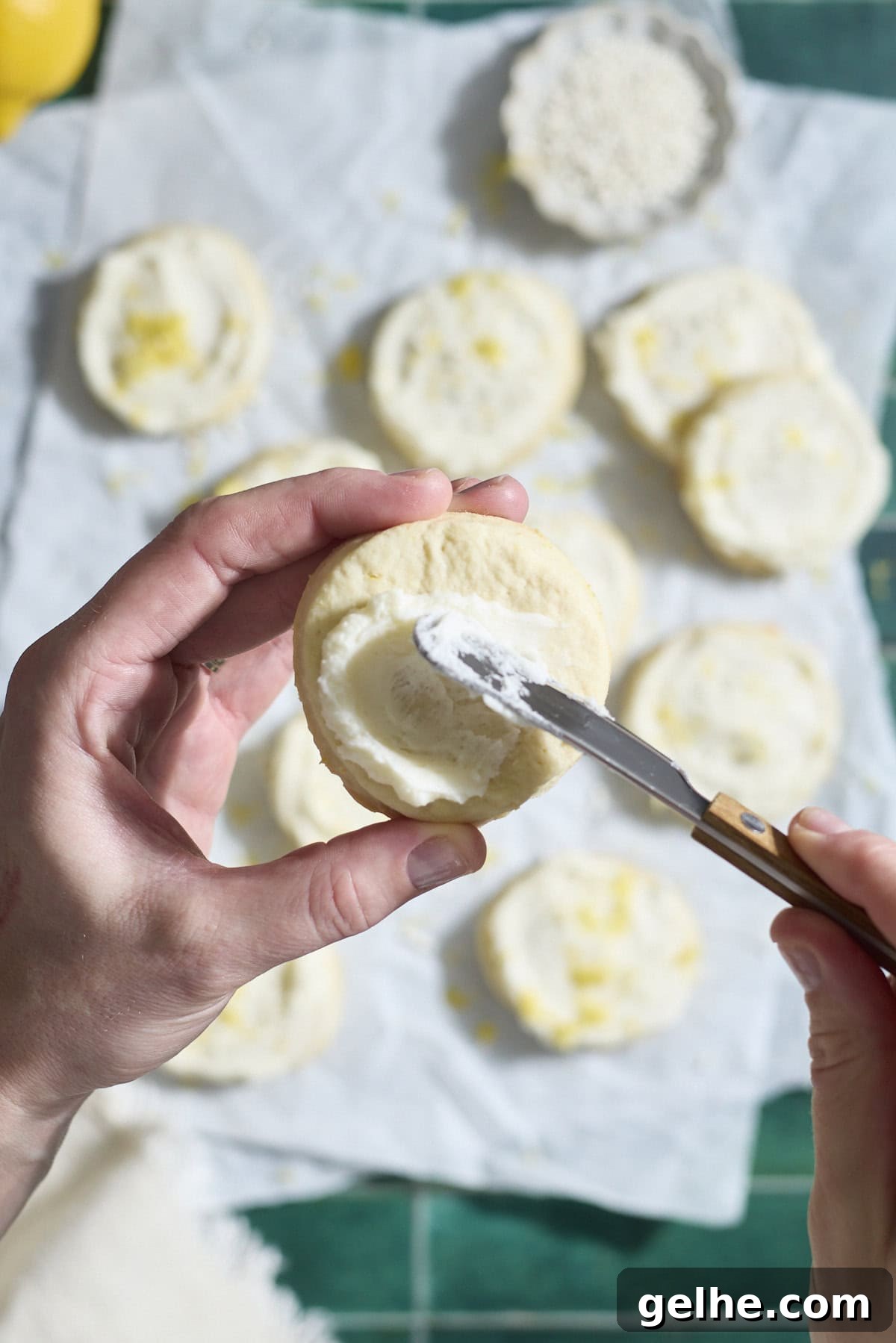 Lemon Sugar Cookies Made with Sourdough Discard 13 A hand spreading a cookie with frosting.