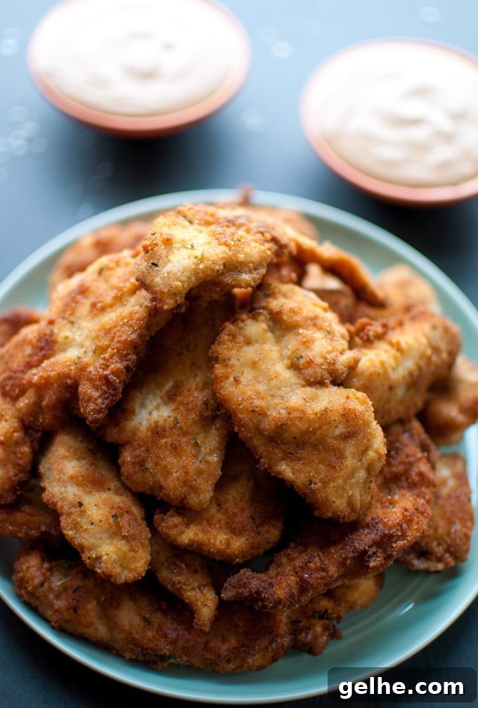 Crispy Breaded Chicken Tenders with 3-Ingredient Dipping Sauce 2 several breaded chicken tenders on a plate beside two small bowls of dip