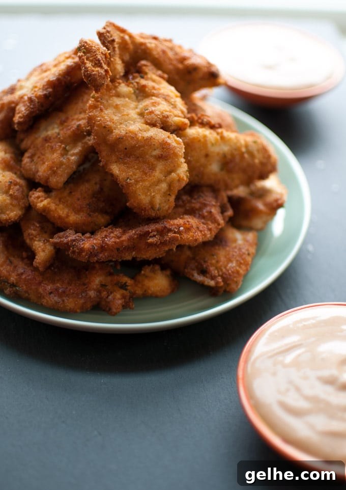 Crispy Breaded Chicken Tenders with 3-Ingredient Dipping Sauce 4 stack of breaded chicken tenders on a plate with close-up of dip in small bowl