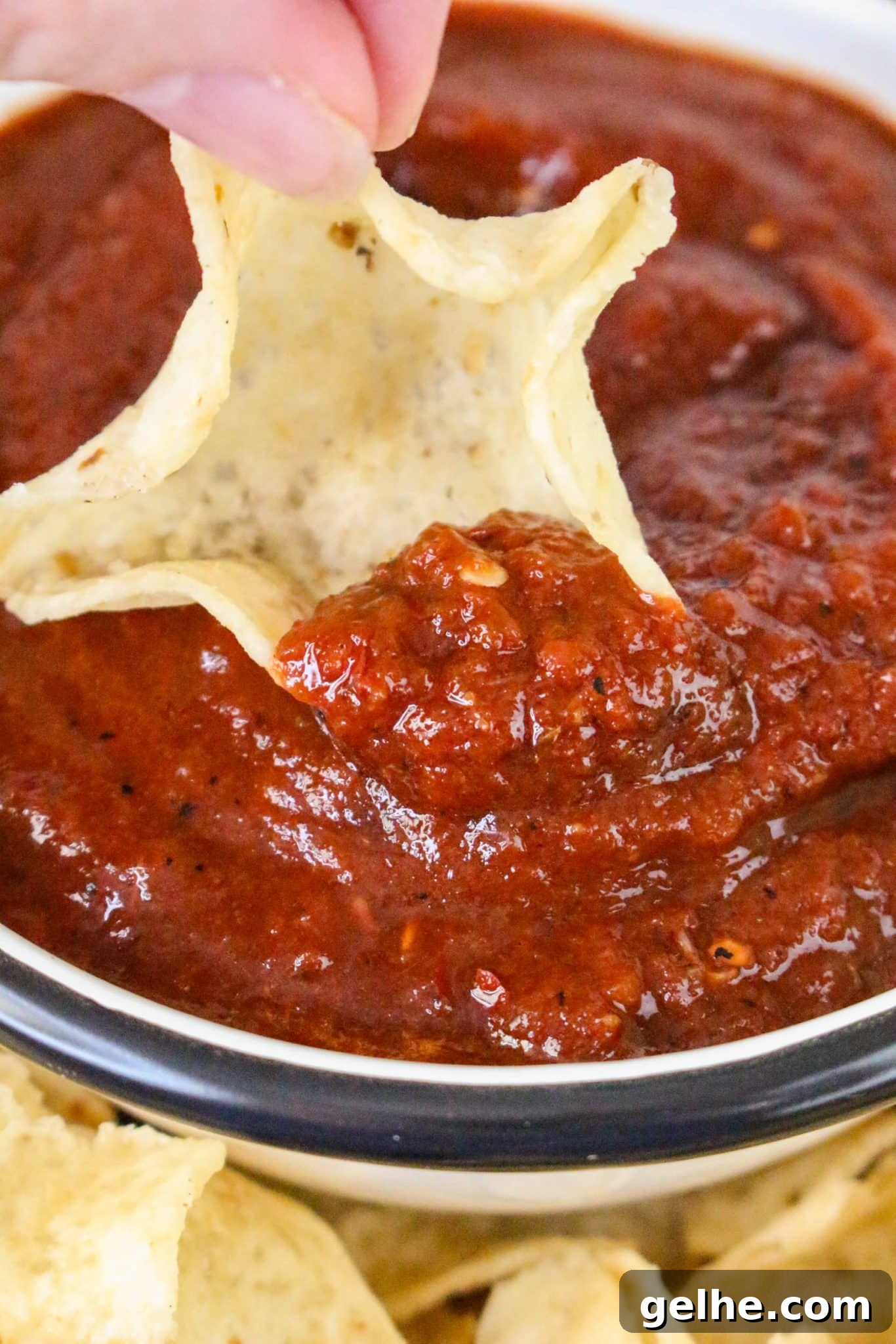 Authentic Red Salsa Roja with Dried Chiles Recipe 9 Close up view of a chip scooping a serving of blended salsa roja recipe - Hostess At Heart