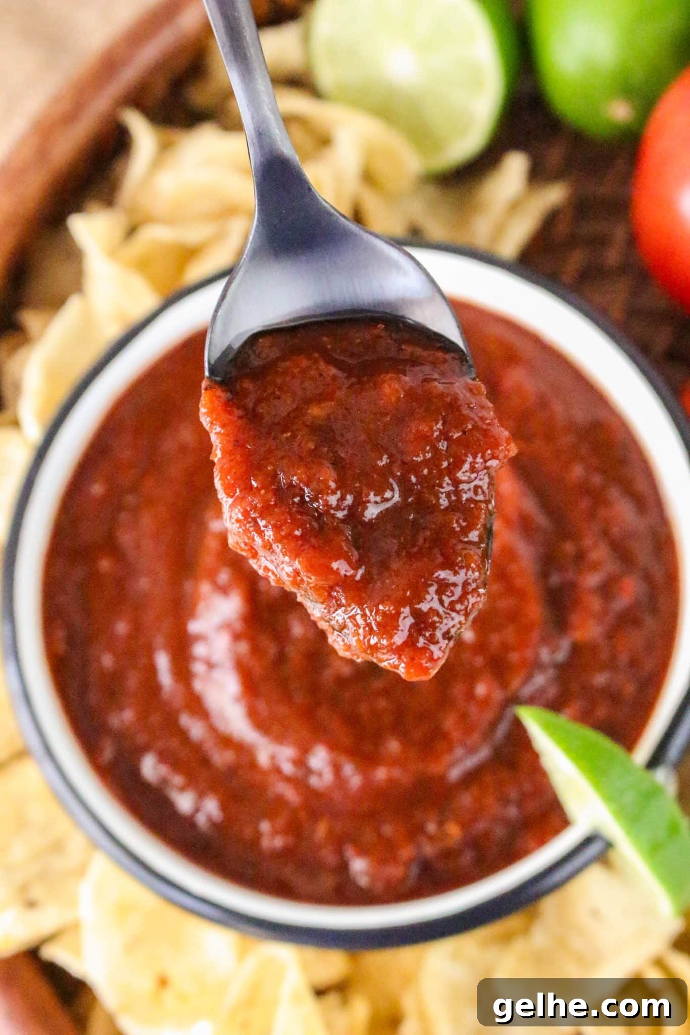 Authentic Red Salsa Roja with Dried Chiles Recipe 7 A bowl of thick blended rojo salsa on a spoon hovering over a bowl - Hostess At Heart