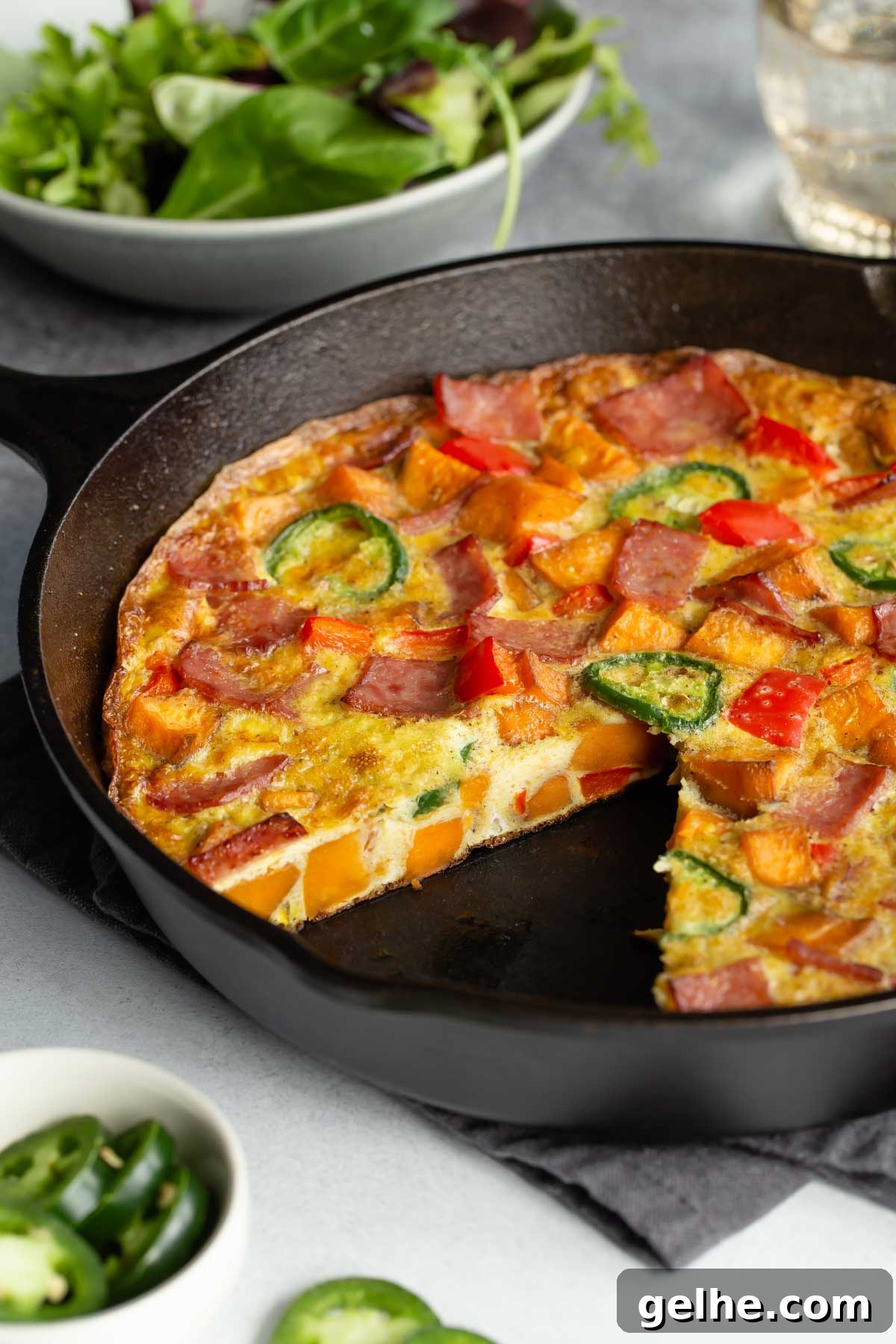 Close up side view of the frittata in a skillet with a slice removed.