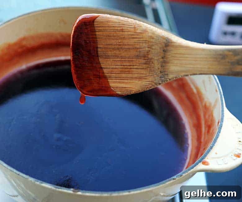Cranberry Barbecue Turkey Burnt Ends Recipe 9 wooden spoon with drip of barbecue sauce coming off over pan.