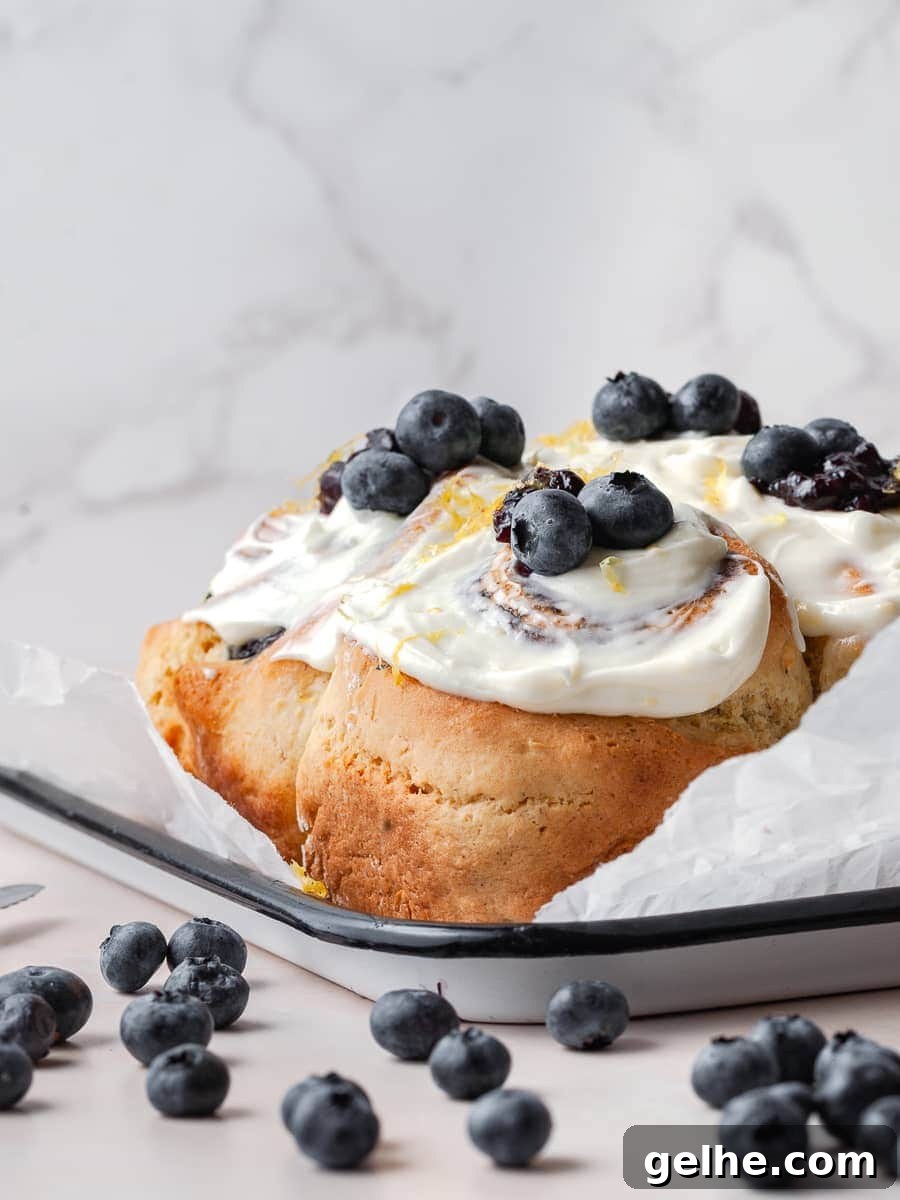 Gluten-Free Blueberry Sweet Rolls Recipe for Soft, Fluffy Buns 2 gluten free blueberry cinnamon rolls topped with lemon cream cheese frosting and fresh blueberries and lemon zest, blueberry sweet rolls