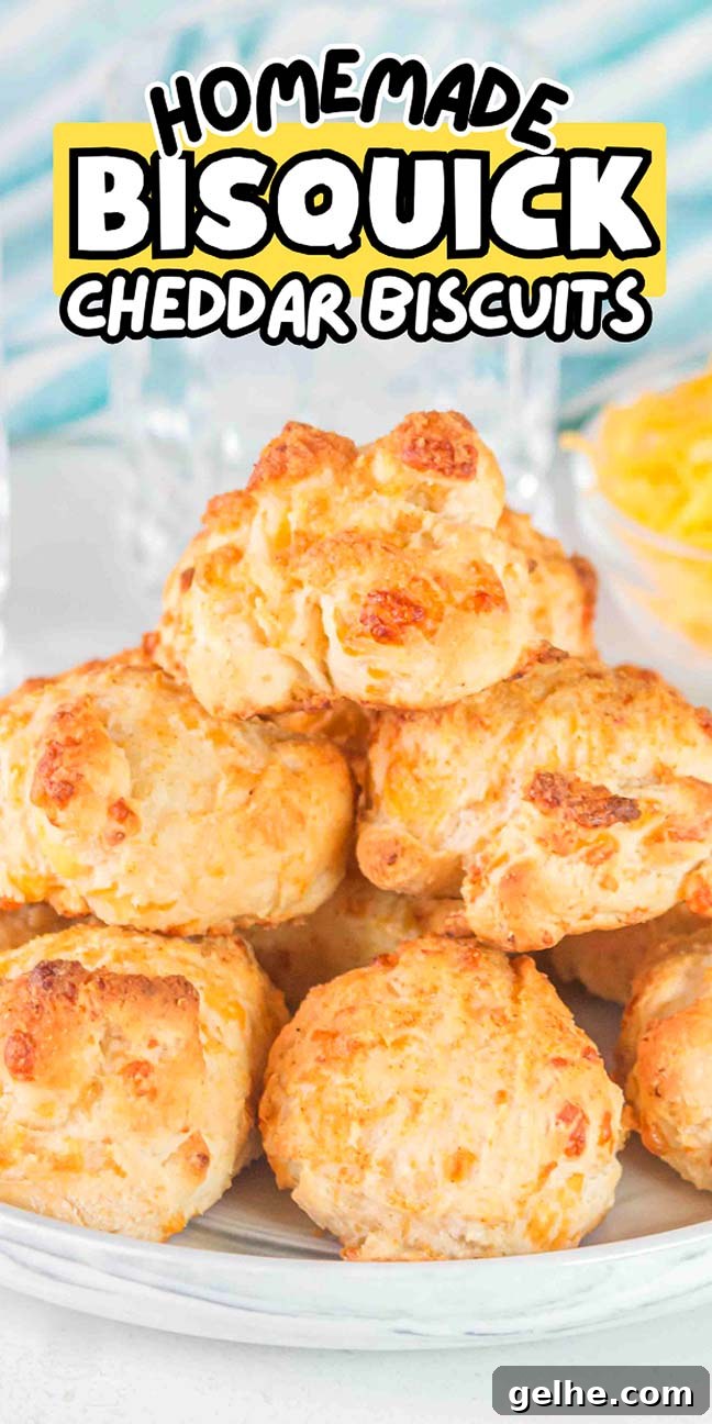 Flaky Cheddar Biscuits Made with Bisquick 19 A plate of golden homemade Bisquick cheddar biscuits stacked high, with a small bowl of shredded cheese in the background.