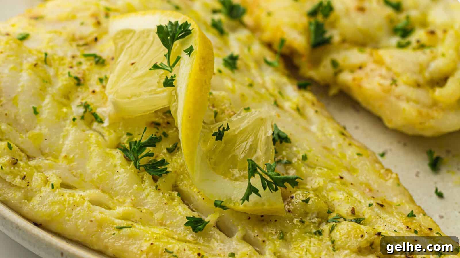 Image of cooked air fryer cod fillets seasoned with herbs and garnished with lemon wedges and parsley on a plate.