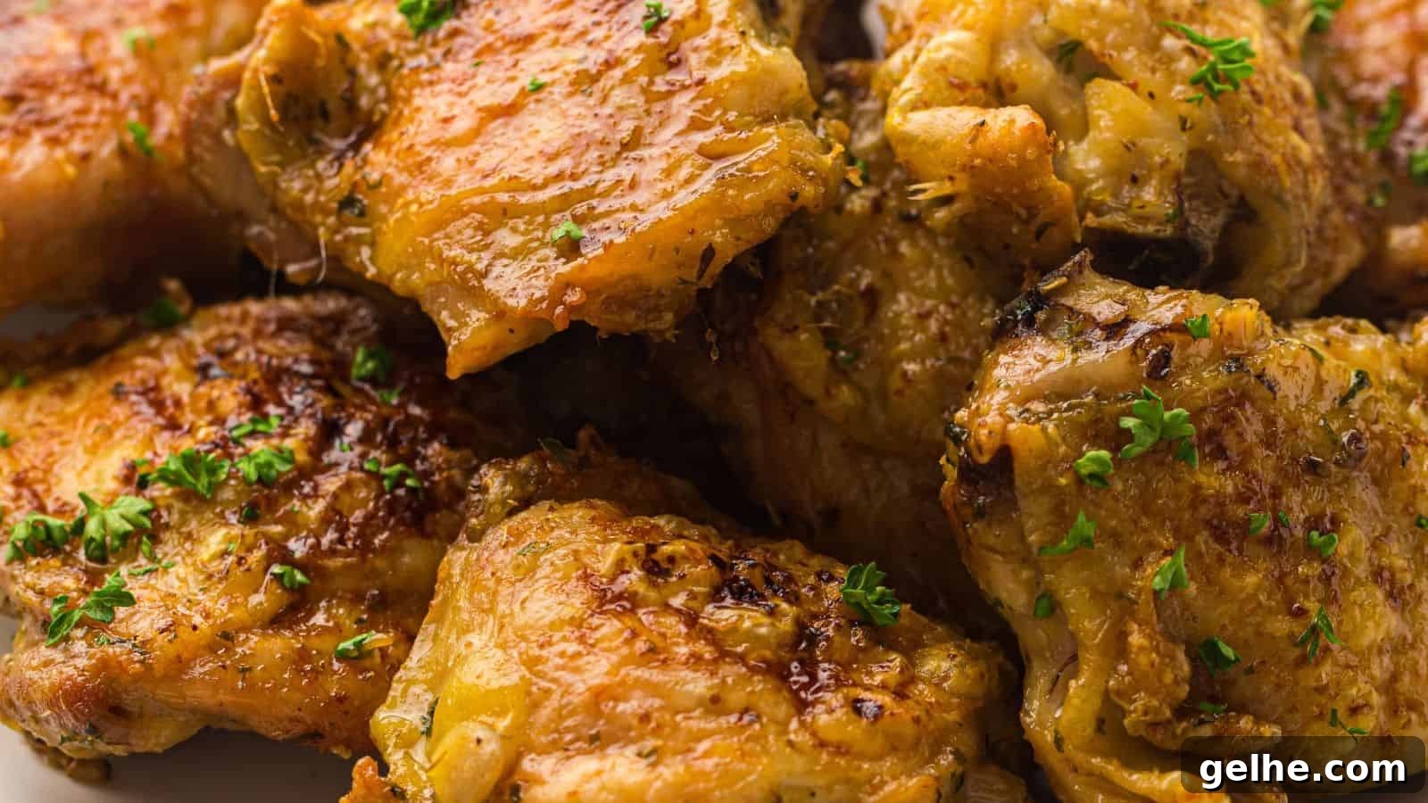 Close-up of cooked chicken thighs, seasoned with herbs and garnished with chopped parsley.