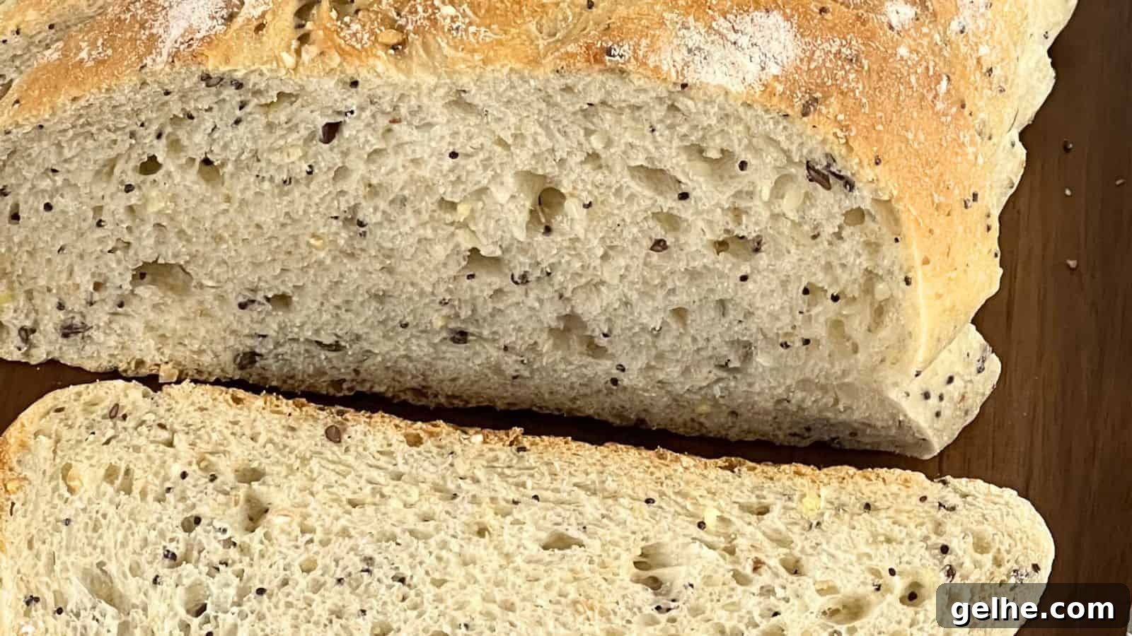 Close-up of a loaf of bread with visible seeds, partially sliced to reveal the texture of the interior crumb.