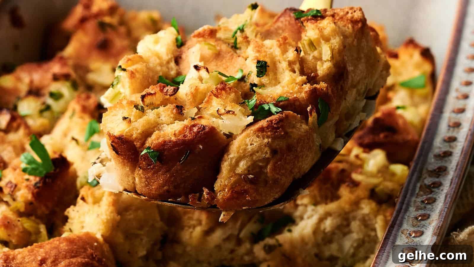 A close-up of a serving of bread stuffing with chopped herbs, lifted from a baking dish.