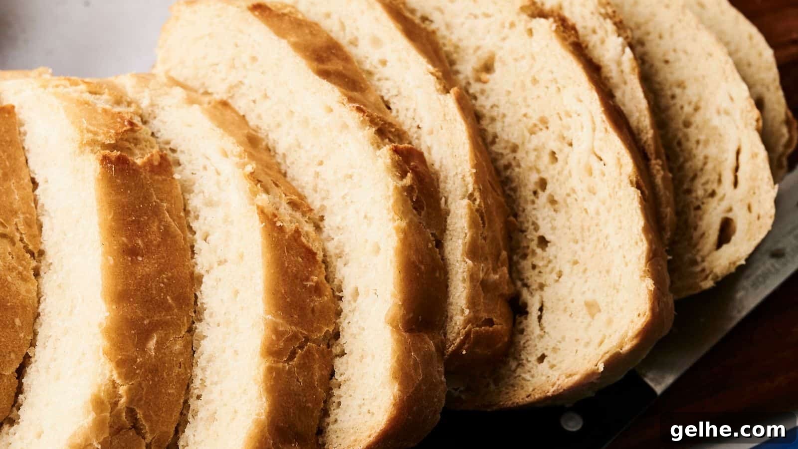 Sliced loaf of bread on a cutting board with a knife beside it.