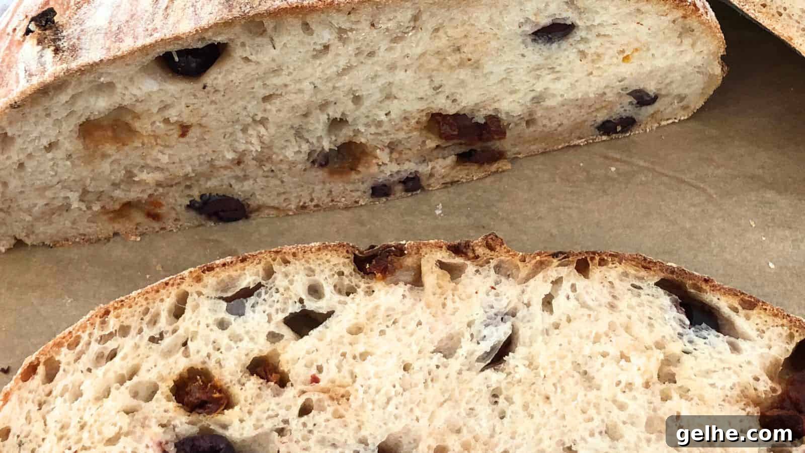 Close-up of sliced olive bread on a cutting board, showing the interior texture and olives embedded in the loaf.