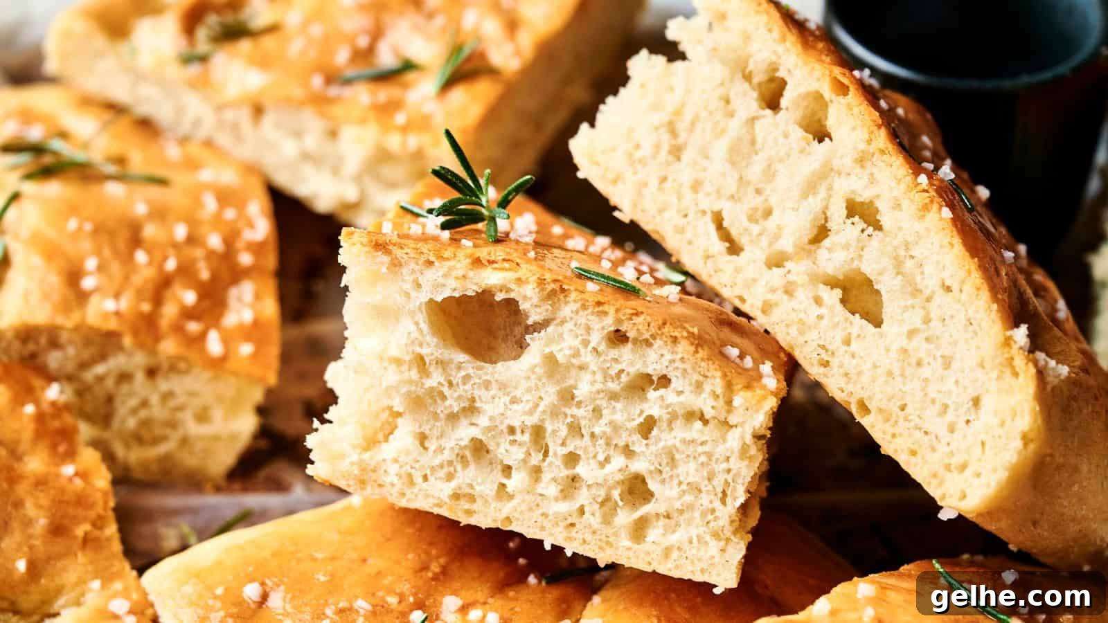 Close-up of sliced focaccia bread topped with coarse salt and rosemary, showing a light, airy crumb.