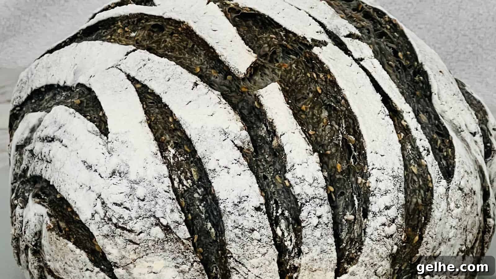 A close-up of a round loaf of bread with a dark crust and white flour stripes, giving a zebra-like pattern.