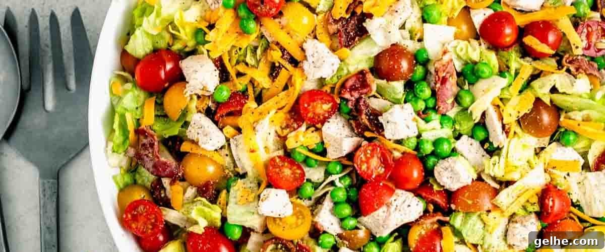 Chopped salad with chicken in white bowl.