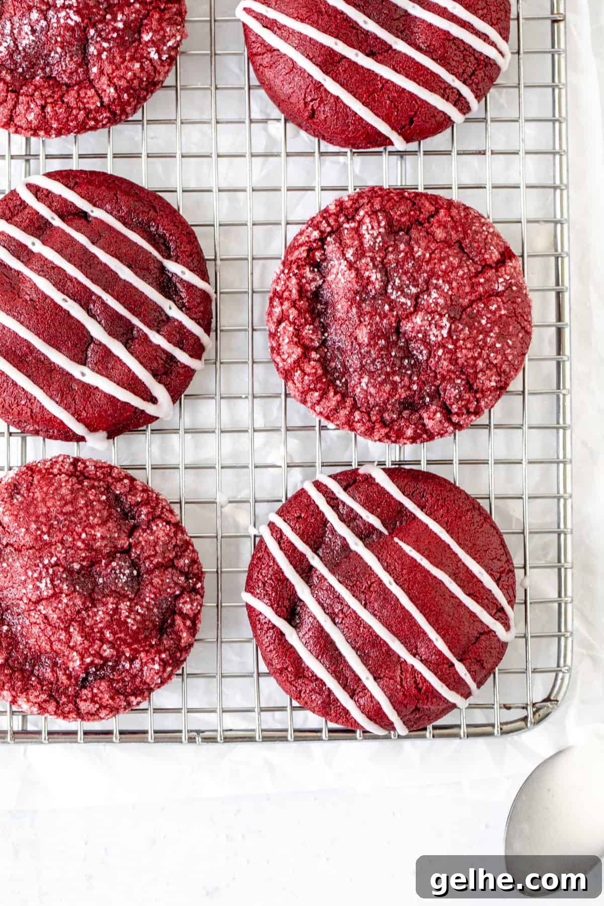 Red velvet cookies on a cooling rack, some cookies drizzled with glaze and some rolled in sugar