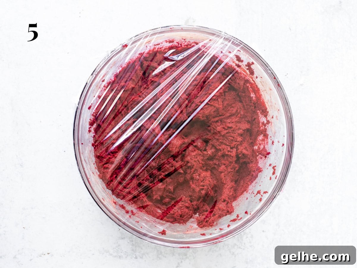Bowl of red velvet cookie dough, covered in plastic wrap