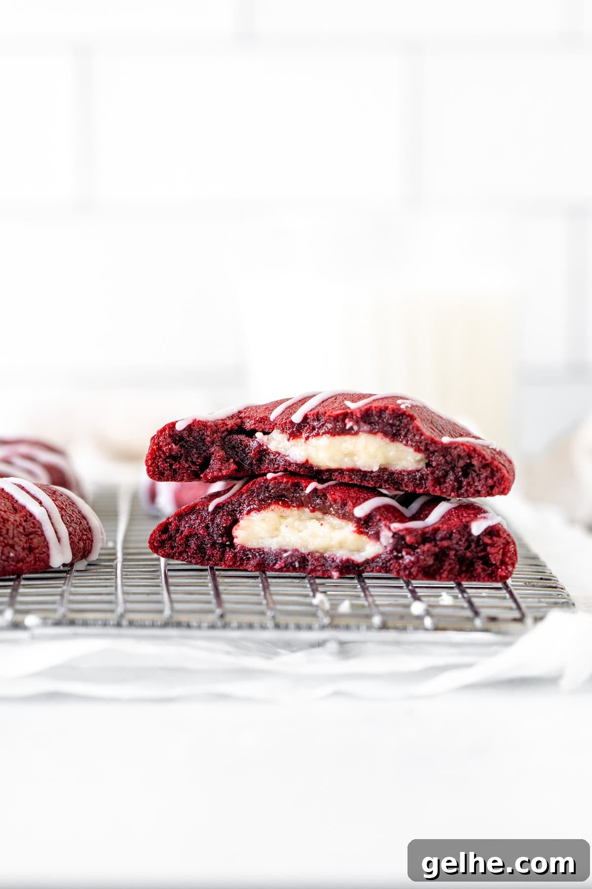 Red velvet cheesecake cookie broken in half on cooling rack